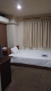 a bedroom with a white bed and a window at ビジネスホテル ごとう＠ＮＥＴ in Kure