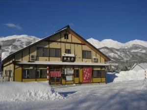 un grand bâtiment avec de la neige devant lui dans l'établissement Nagomi-tei, à Hakuba