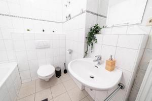 a white bathroom with a sink and a toilet at Full House Apartment MCity L10 in Magdeburg