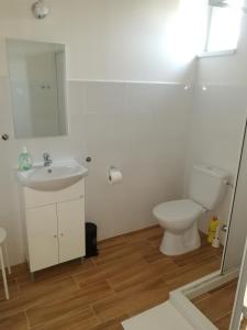 a white bathroom with a toilet and a sink at Zsuzsanna Vendégház in Gyomaendrőd