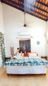 a woman sitting on a bed in a bedroom at Casa Brooklyn Portuguese Heritage in Saligao