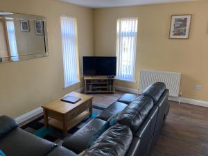 a living room with a leather couch and a television at Station House in Merthyr Tydfil