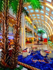 a lobby with two palm trees and tables and chairs at Bayshore Hotel Dalian in Dalian