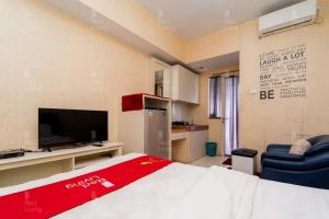 a room with a bed and a tv and a couch at RedLiving Apartemen Green Lake View Ciputat - Pelangi Rooms 2 Tower E in Tangerang