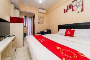 een hotelkamer met een bed met een rode deken bij RedLiving Apartemen Green Lake View Ciputat - Pelangi Rooms 2 Tower E in Tangerang