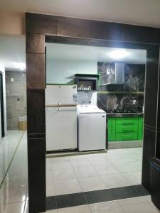 La cuisine est équipée d'un réfrigérateur blanc et de placards verts. dans l'établissement Habitación Irving confortable con baño privado, à Mexico