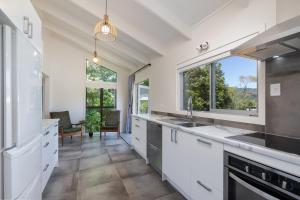 a kitchen with white cabinets and a large window at Cobham Crib - Anakiwa Holiday Home in Anakiwa