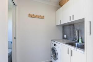 a white kitchen with a sink and a washing machine at Cobham Crib - Anakiwa Holiday Home in Anakiwa