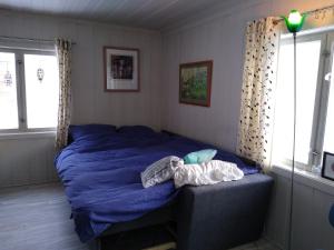 a bedroom with a bed with blue sheets and windows at Furuly vakantiehuis in Vingelen