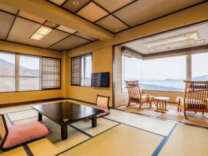 sala de estar con mesa, sillas y TV en Kishigon Ryokan, en Shibukawa