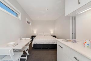a white bedroom with a bed and a desk at The Orchard House - Turangi Holiday Home in Turangi