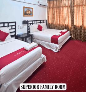 two beds in a hotel room with red carpet at ASLAH BOUTIQUE HOTEL in Kota Bharu