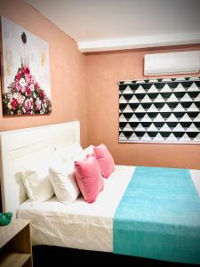 a bedroom with a bed with pink and white pillows at Monaco villa Palapye in Palatswe