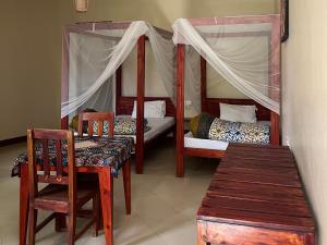 1 dormitorio con 2 literas, mesa y sillas en Charming Bungalows en Mwanza