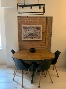 a wooden table and chairs in front of a brick wall at Apartament Warszawska 33 in Mrągowo
