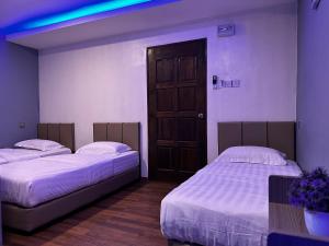 two beds in a room with a door at Cow B Homestay Semporna in Semporna