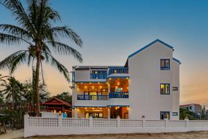 a white house on the beach with a palm tree at LOCAL BEACH FRONT VILLAS in Tân Thành (1)