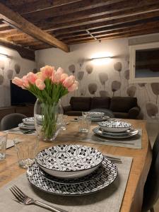 une table avec des assiettes et un vase de fleurs dans l'établissement Ca' Rosa Charming Suite, à Venise