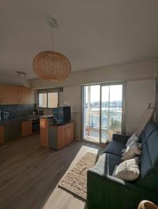 un soggiorno con divano blu e una cucina di Nina studio 5 Places avec vue sur la baie au pied des commerces Classé 3 étoiles a Pornichet