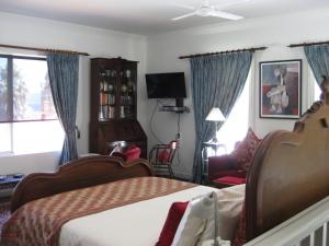 a bedroom with a bed and a chair and a tv at Three Chimneys Bed and Breakfast Boutique Guest House in Albany