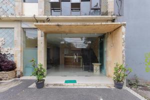 an open door of a building with two potted plants at Urbanview Hotel WG Jimbaran Bali in Ungasan