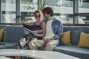 a man and woman sitting on a couch reading a book at Lyttos Mare in Hersonissos