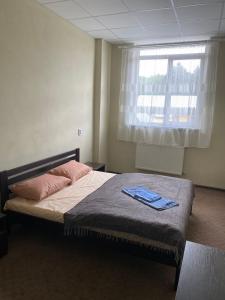 Schlafzimmer mit einem Bett mit rosa Kissen und einem Fenster in der Unterkunft Ластівка in Chust