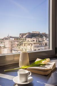 una mesa con una taza de café, un libro y una ventana en Aria Acropolis Suites, Troulanda, en Atenas