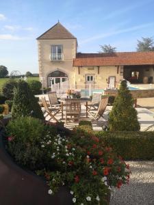 - un jardin avec des chaises et des fleurs devant une maison dans l'établissement La Tour D'Elaine, 