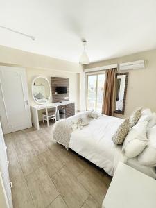 Schlafzimmer mit einem großen weißen Bett und einem Schreibtisch in der Unterkunft Antonis G. Hotel Apartments in Oroklini