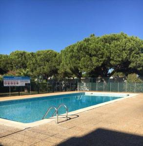 uma piscina com árvores e uma cerca à volta em Appartement climatise - grande terrasse em Le Grau-du-Roi