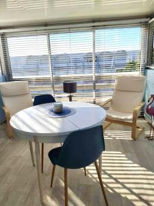 uma mesa branca e cadeiras num quarto com uma janela em Appartement climatise - grande terrasse em Le Grau-du-Roi