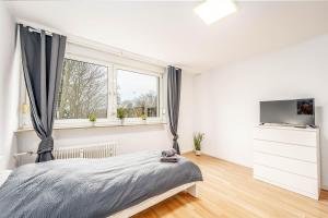 um quarto com uma cama, uma televisão e janelas em Cosy Apartment near Lippstadt em Geseke