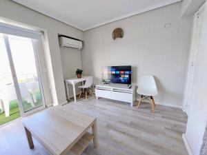 uma sala de estar com uma televisão e uma mesa em Apartamentos Strand Jávea em Xàbia