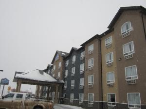 een vrachtwagen geparkeerd voor een gebouw in de sneeuw bij Lakeview Inns & Suites - Fort Nelson in Fort Nelson