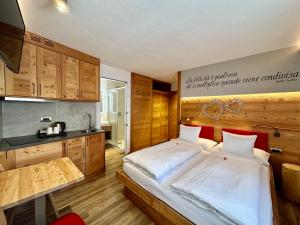 a bedroom with a large bed and a kitchen at B&B C&egrave;sa Planber Mountain View BIKE FRIENDLY in Canazei