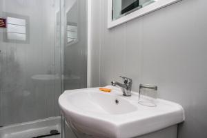 a white bathroom with a sink and a shower at SleepOver Lanseria in Lanseria