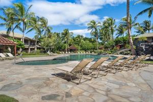 a row of lounge chairs next to a swimming pool at Big Island Fairways at Mauna Lani 1705 townhouse in Waikoloa