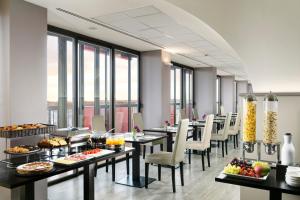un restaurante con mesas y sillas con comida. en UNAWAY Hotel & Residence Contessa Jolanda Milano, en Milán