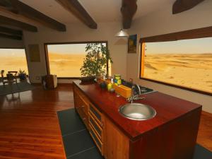 een keuken met een wastafel en uitzicht op de woestijn bij Desert Breeze Lodge in Swakopmund