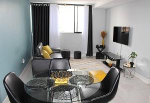 a living room with a glass table and black chairs at Favour's 2 Bedroom Apartment on 77 in Windhoek