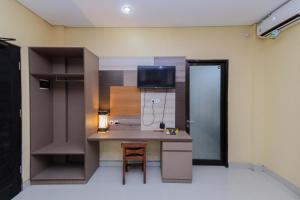 a room with a desk and a tv on a wall at Urbanview Hotel WG Jimbaran Bali in Ungasan