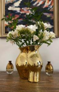a gold vase with white flowers in it on a table at historical Zaffir house - market square in Levoča