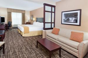 Holiday Inn Express Hotel & Suites Jackson Northeast, an IHG Hotel في جاكسون: غرفه فندقيه بسرير واريكه