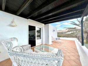 een patio met een witte rieten stoel op een balkon bij Suite only adults with Breakfast included, FreeWifi, shared pool, ocean view in Yaiza in Yaiza