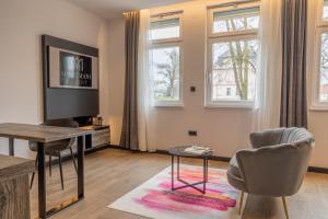 ein Wohnzimmer mit einem Tisch, Stühlen und Fenstern in der Unterkunft Apartmani Mozart-centar Virovitica in Virovitica