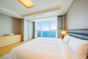 - une chambre avec un grand lit et une grande fenêtre dans l'établissement LCT Residence Y collection, à Busan