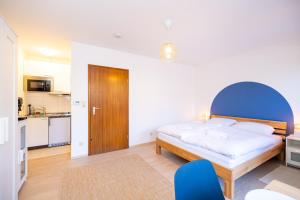une chambre avec un lit avec une tête de lit bleue et une cuisine dans l'établissement Nettes Apartment mit Terrasse, à Wurtzbourg