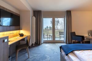 ゲーレンにあるSanté Royale Rügen Resortのベッド、デスク、バルコニーが備わるホテルルームです。