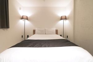 a bedroom with a large white bed with two lamps at HOTEL WHEAT WACCA in Sapporo